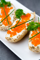 Red caviar on bread on white plate.