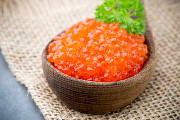 Salmon caviar with spoon on gray background.