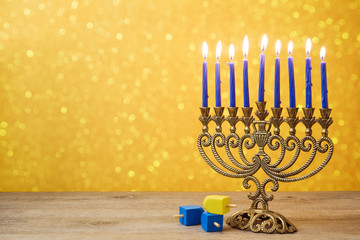 Naklejka premium Jewish holiday Hanukkah background with vintage menorah and spinning top dreidel over lights bokeh.