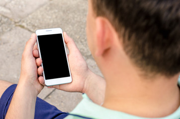 White mobile phone holding a young hipster man in business shirt mint color on purple wooden background
