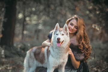 Girl playing with her husky dog in the park, autumn. Fashion blonde stylish woman. Outdoors. Beauty nature. Farytale. 