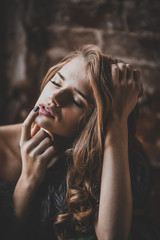 Close-up portrait of an attractive young woman by a dark grunge background. Beauty, fashion. Cosmetics, dark make-up. Long hair.