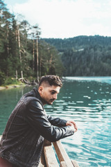 Man thinking on pier by a lake with trees and mountains - 121651700