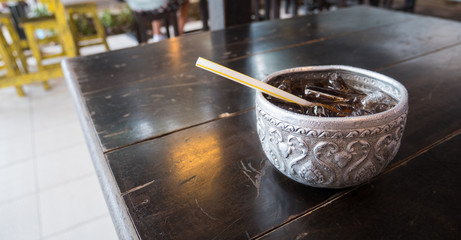 Water bowl cola with ice on wood table on a hot day of Summer