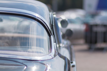 Close-up of an old car. Part of the exterior. An American classic. Chrome lining. Glass with reflection.