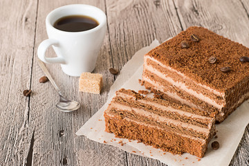 Dessert.  Pieces of chocolate cake on parchment paper, cup of coffee and spoon on a gray wooden table.
