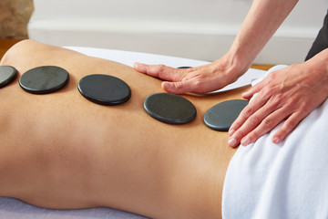 Obraz na płótnie Canvas Hot stone massage in woman back physiotherapist