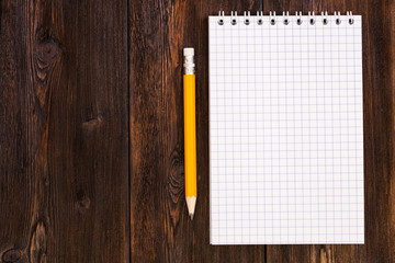 Blank notebook and pencil on a wooden background