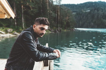 Man thinking on pier by a lake with trees and mountains - 121658330
