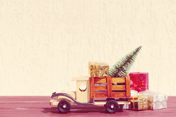 Christmas background.Toy truck carries gifts and a Christmas tree. Photo in vintage style