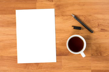 Blank paper is on top of wood table with pen and cup of coffee,