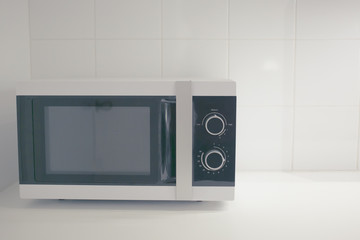 Fototapeta premium microwave in clean kitchen in vintage soft tone,simple life style concept.