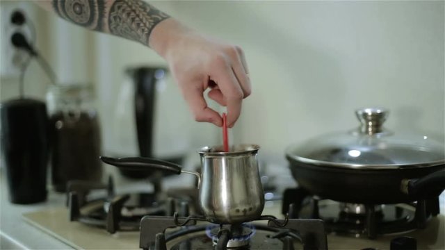 A man with tattoos stirring coffee using a spoon .