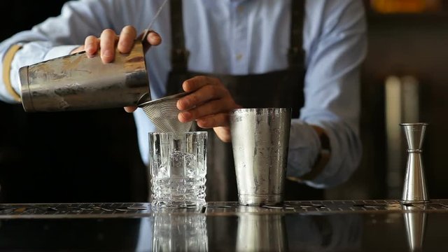 The bartender pours a glass of the finished cocktail