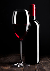 Red wine bottle and glass on wooden table black