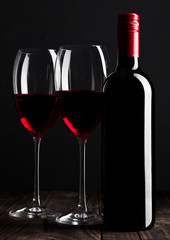 Red wine bottle and glasses on wooden table black