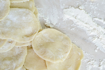 The dough rolled with circles, sprinkled flour. Making of pierog.