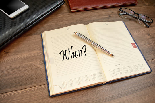 Title when and business accessories on desktop: notebook, diary, fountain pen, mobile phone, glasses.