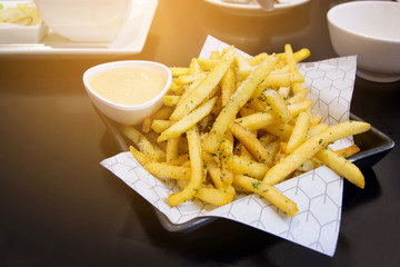 Low key of french fries with sauce on a table and sunshine background.