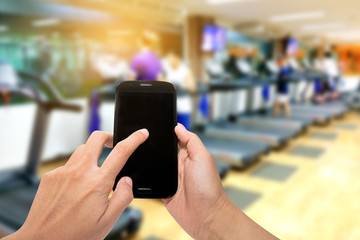 Hand holding smartphone device with sunshine at motion  blur gym background