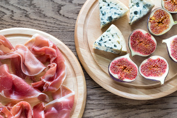 Slices of jamon with blue cheese and figs on the wooden board