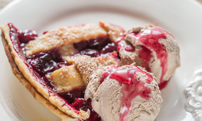 Slice of cherry pie with balls of chocolate ice cream