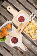 Rectangular  pizza with topping and cheese balls on a wooden table,pizza and cheese balls with knife and spoon ,pizza and cheese balls with sauce.