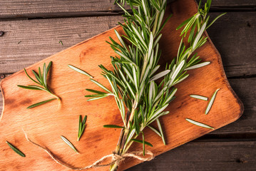 Sprig of rosemary on a wooden table, on cutting board, top view