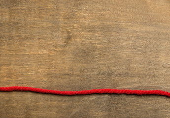 The red thread above vintage wooden background in the lower part