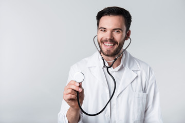Glad bearded man smiling and holding stethoscope.