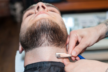 Young man having beard shaven