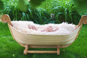 Infant lies in wooden cradle