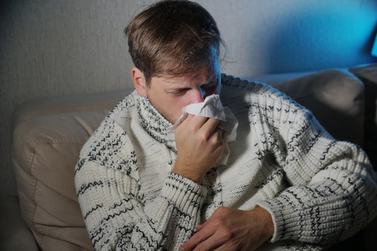 Sick man blowing his nose in the tissue, young ill man in bed

temperature feeling bad infected by winter grippe virus in flu and influenza health care concept
