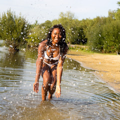 young woman having fun in her bikini splashing water