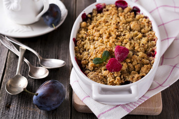 Plum and raspberry crumb on the old wooden background. Rustic style. Selective focus.