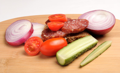 summer sausage , salted cucumber, red cherry tomatoes and sliced red onion Bamboo cutting board , traditional snack while drinking vodka