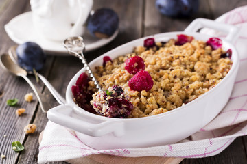 Plum and raspberry crumb on the old wooden background. Rustic style. Selective focus.