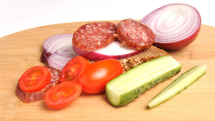 summer sausage , salted cucumber, red cherry tomatoes and sliced red onion Bamboo cutting board , traditional snack while drinking vodka