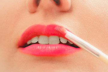 Naklejka premium Woman applying lipstick with brush on lips. Makeup