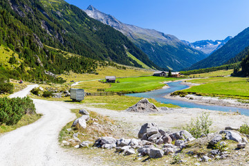Austrian Alps. Starting famous Krimml waterfalls. Crystal clear water sparkles in the midday sun. Through the narrow creek wooden bridge spanned