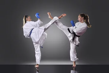 Photo sur Aluminium Arts martiaux Two female young karate fighting on the gray background
