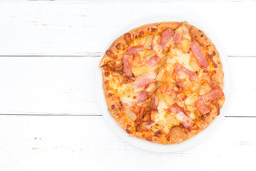 Top view of hawaiian pizza on wooden white table background.