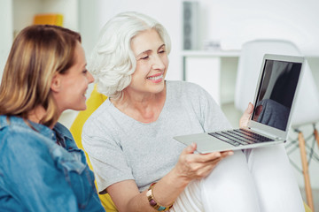 Cheerful delighted senior woman holding laptop