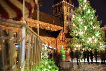 Fototapeta na wymiar Carrousel and Christmas tree at Christmas market in Riga