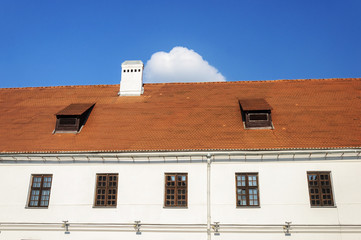 Old tiled roof with two attic windows and chimney