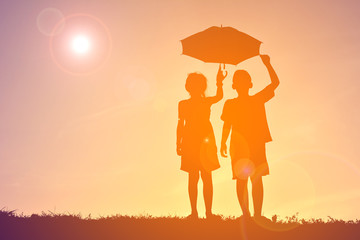 Silhouette children with umbrella on sunset