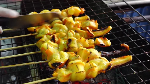 Traditional street food of Thailand. Cooking small squids on the grill