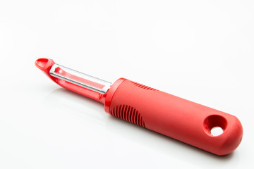 Vegetable peeler with red handle on a white background.