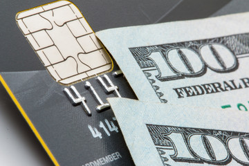 EMV chip on a credit card and $100 dollar bills. - 121686159