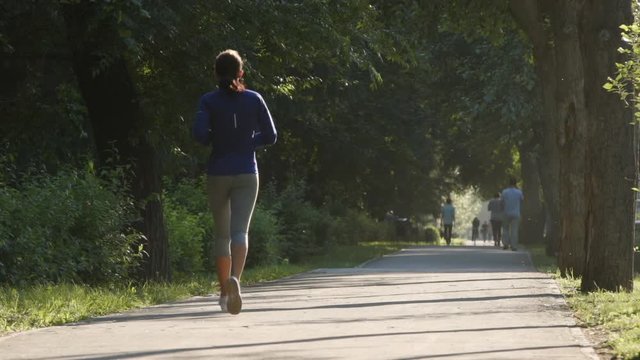 SLOW MOTION: Young woman runs in a park